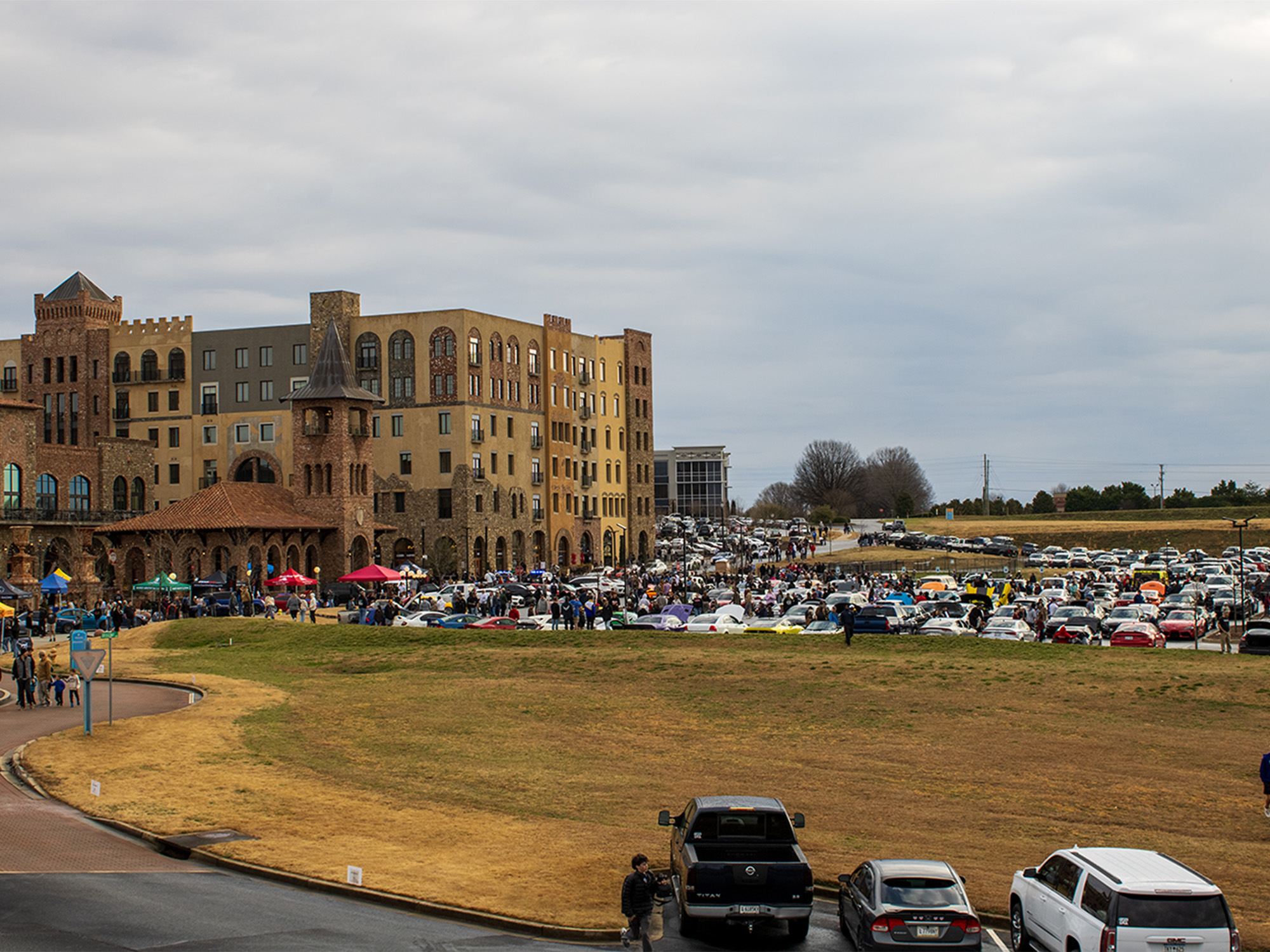 wide angle view of large brick building with car show taking place