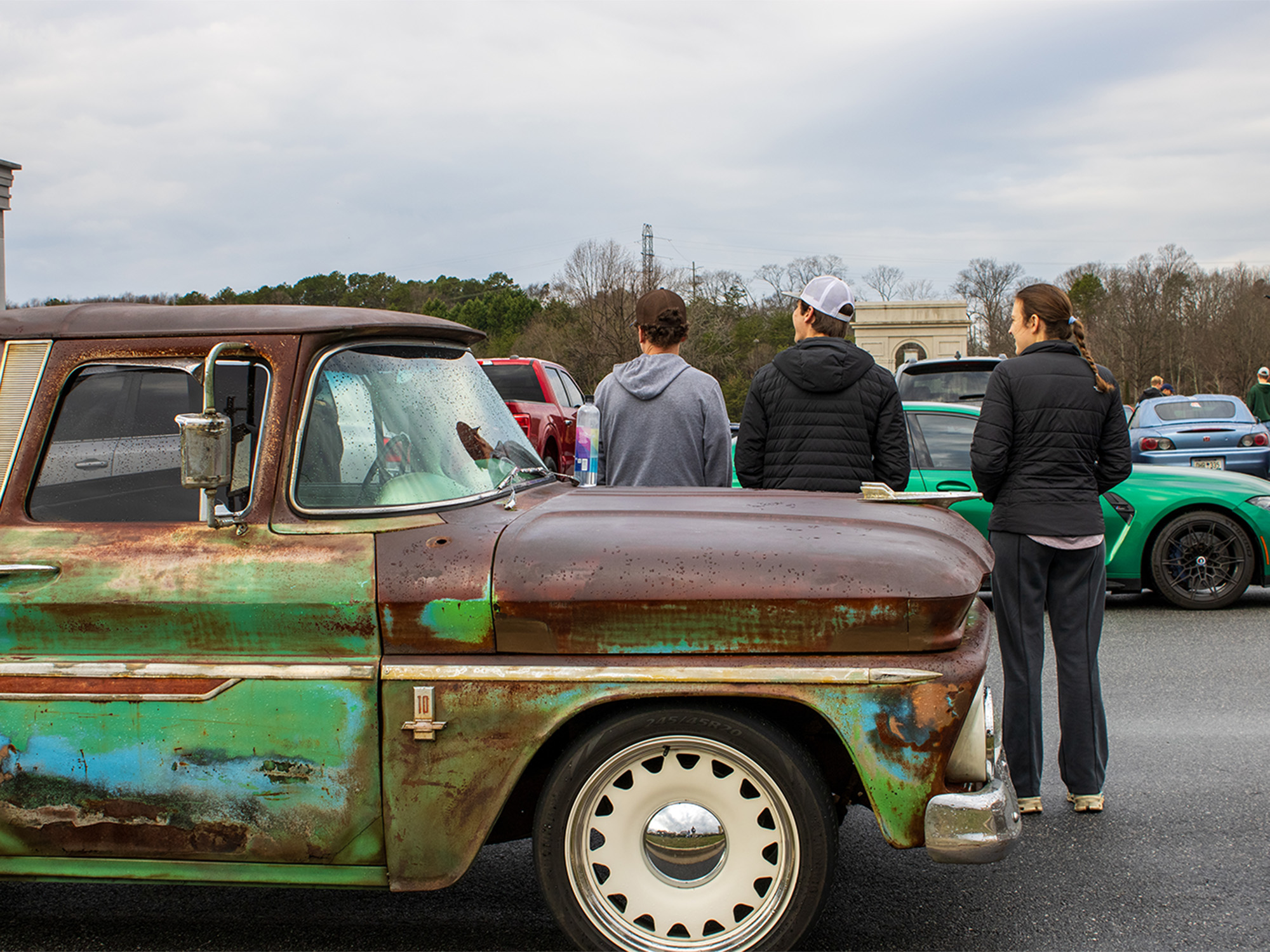 old truck parked at car show with people leaning on the hood