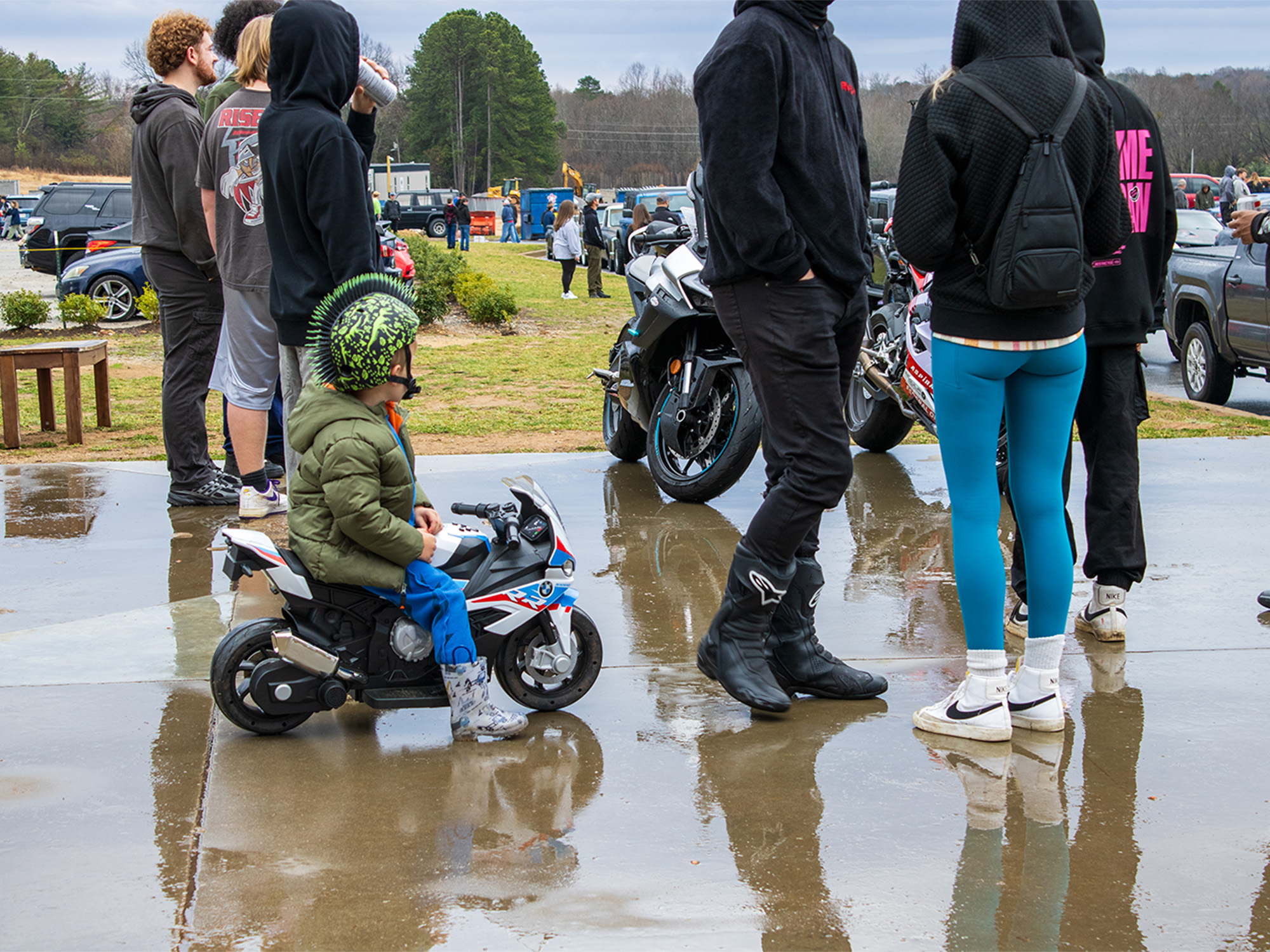 little boy on mini motorcycle powerwheel next to parked motorcycles