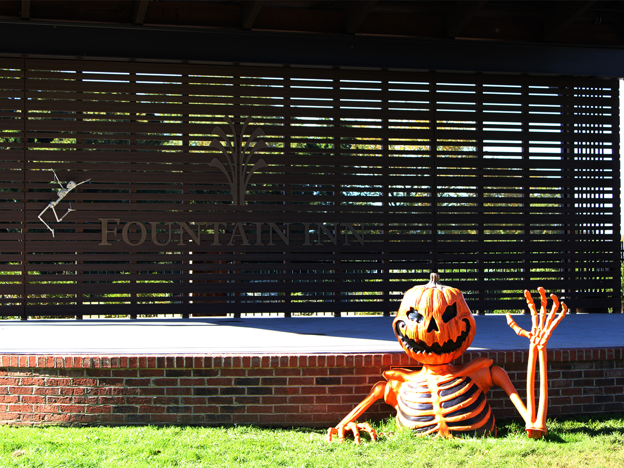 large pumpkin skeleton torso waving in front of small stage outside