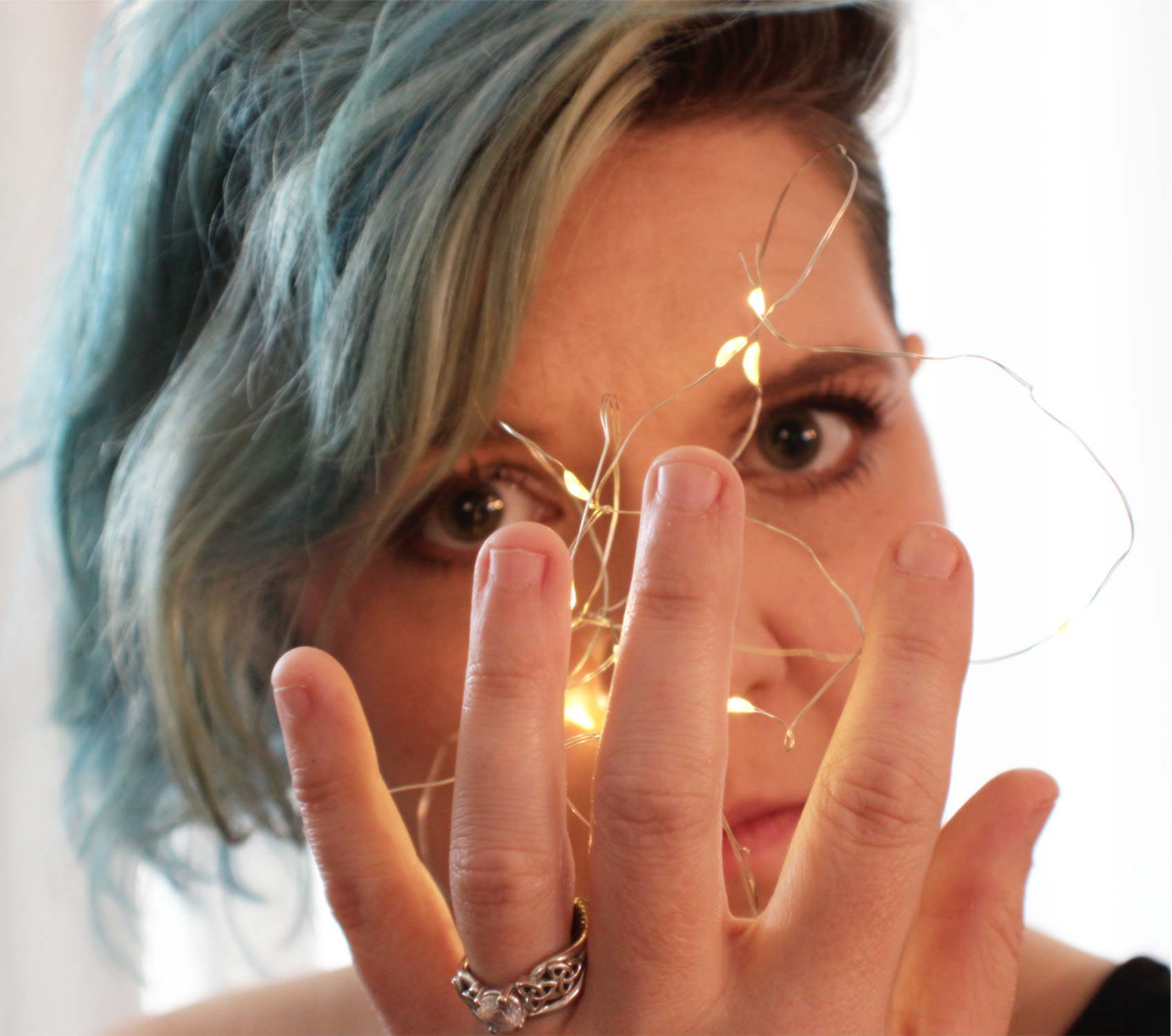 self portrait of woman holding fairy lights in her hand looking at camera