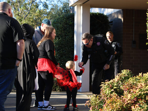 officers handing out halloween candy to a toddler dressed as a ladybug