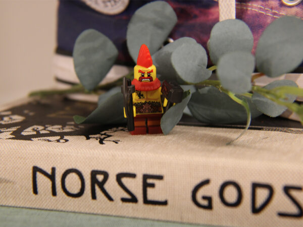 Lego Viking with axe and hammer standing on norse mythology books