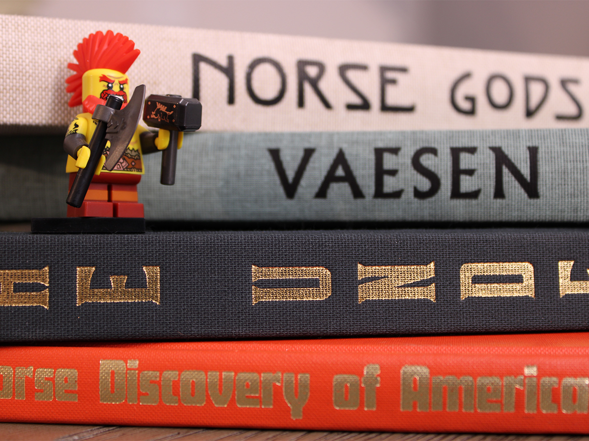 Lego Viking with axe and hammer standing on stack of norse mythology books