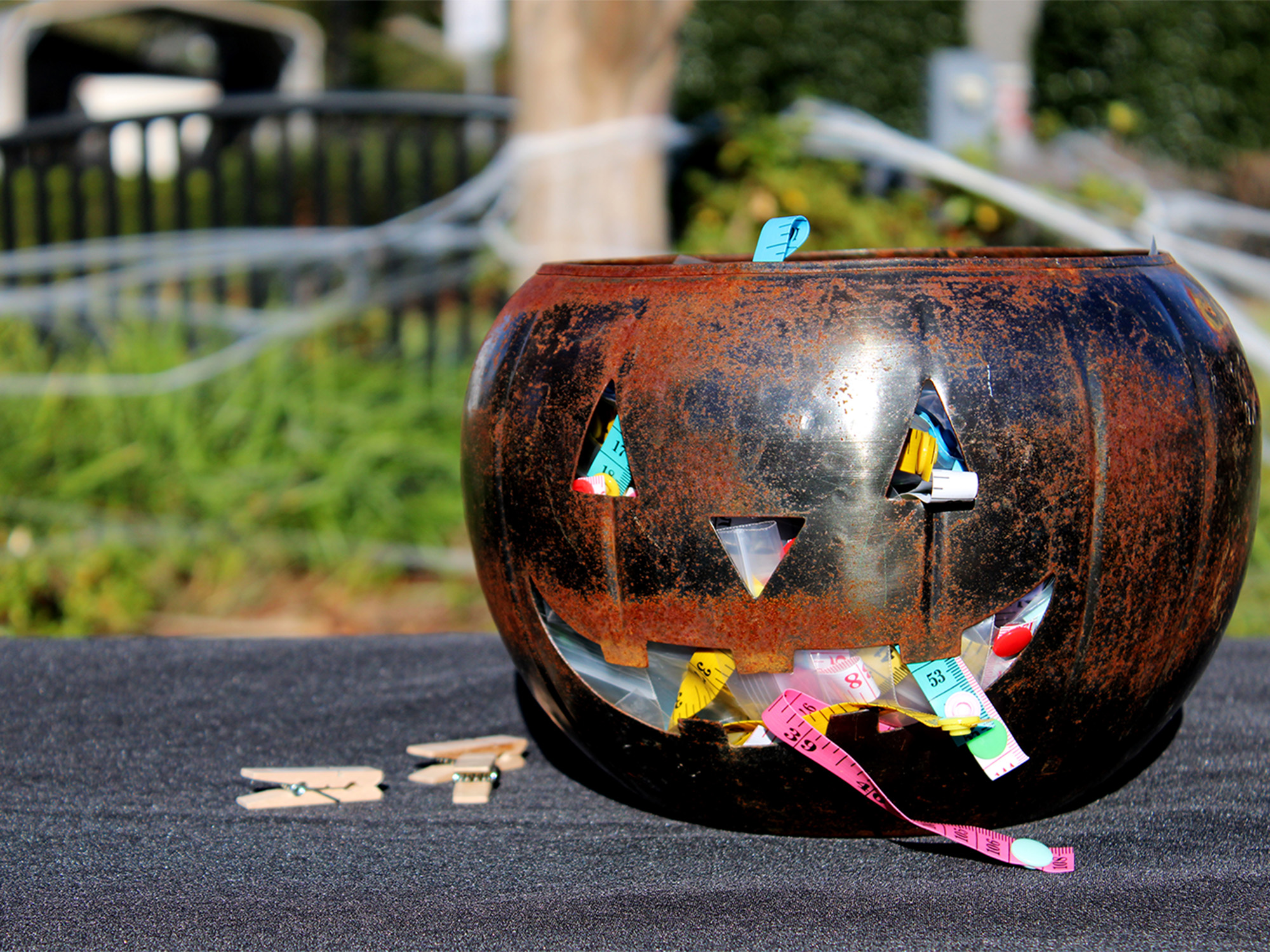 metal jack-o-lantern on table with sewing accessories coming out of its mouth