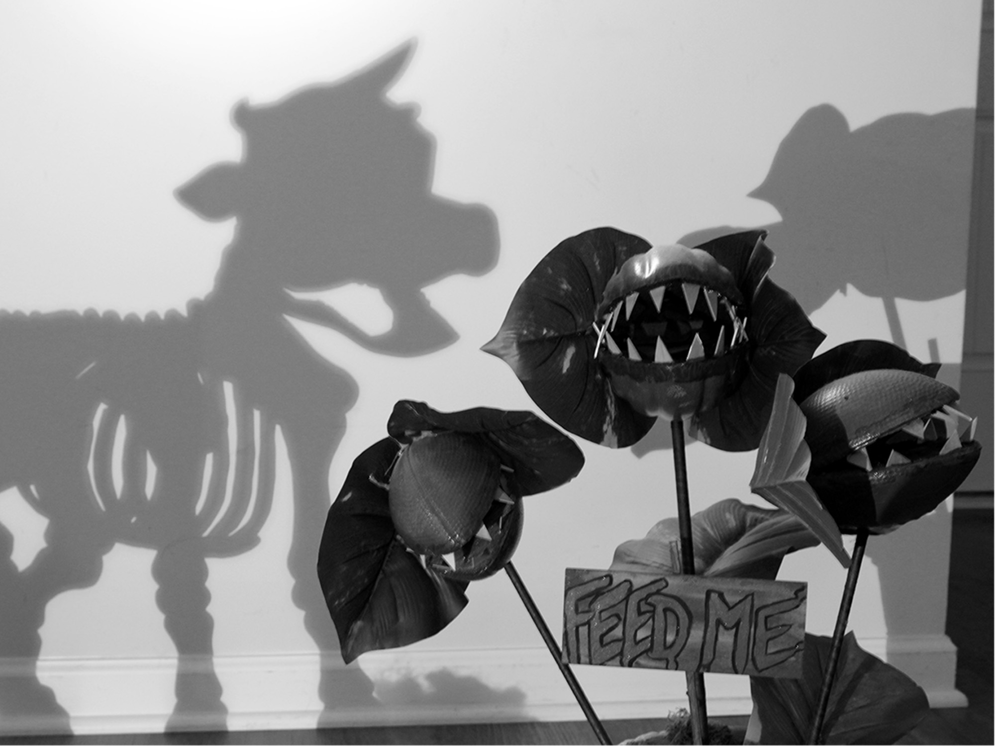 shadow of a skeleton cow trying to eat a scary plant with feed me sign
